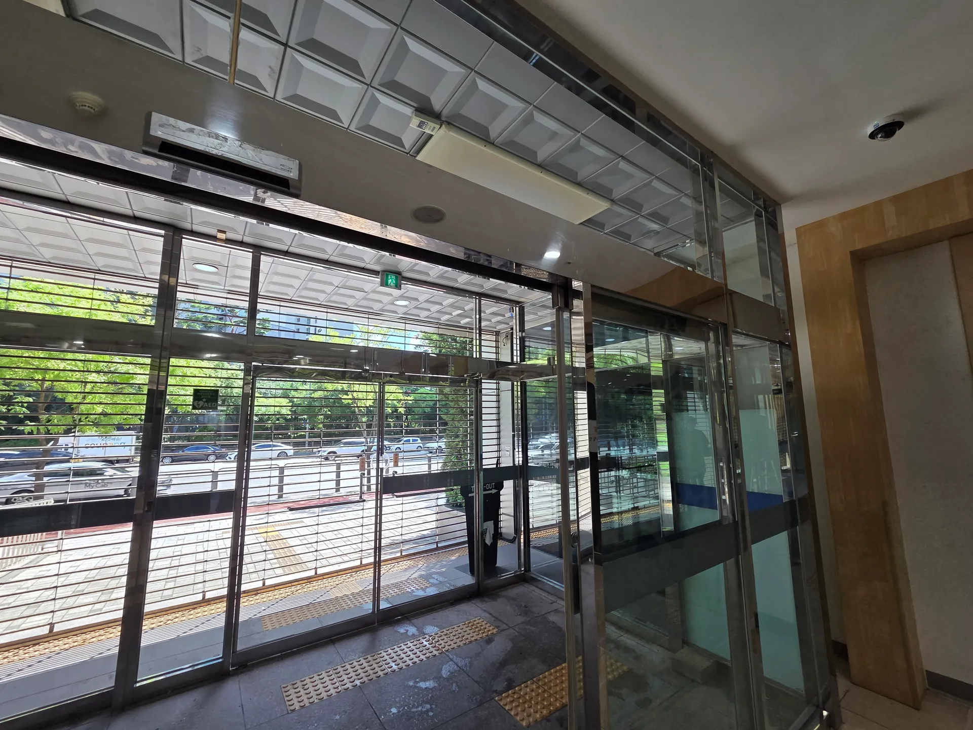 상부 금속 띠와 유리문 및 세로 프레임의 반사선이 이어진 입구 전면