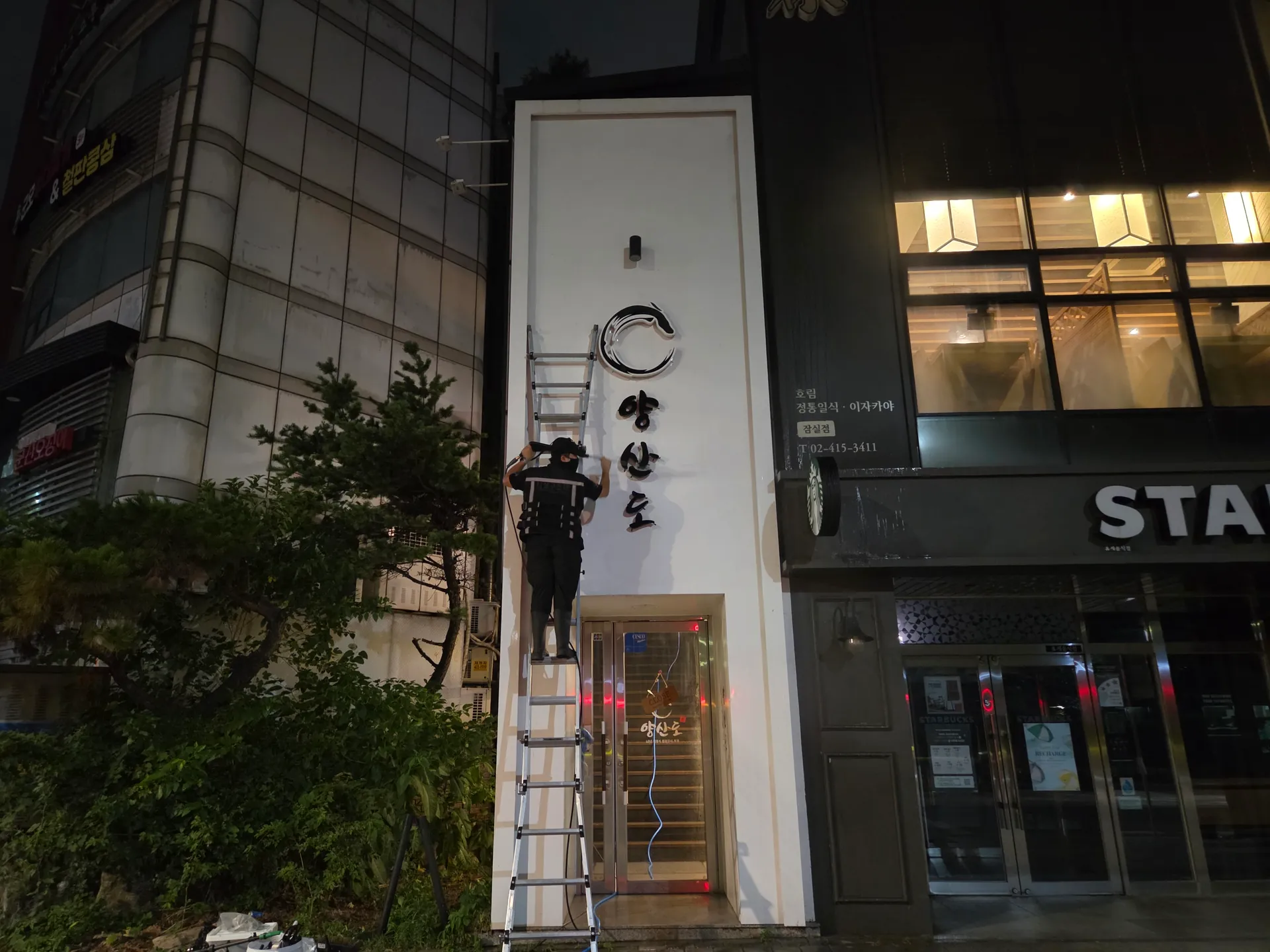 유리 출입문 위 금속 프레임과 세로형 외벽을 이어서 관리한 모습