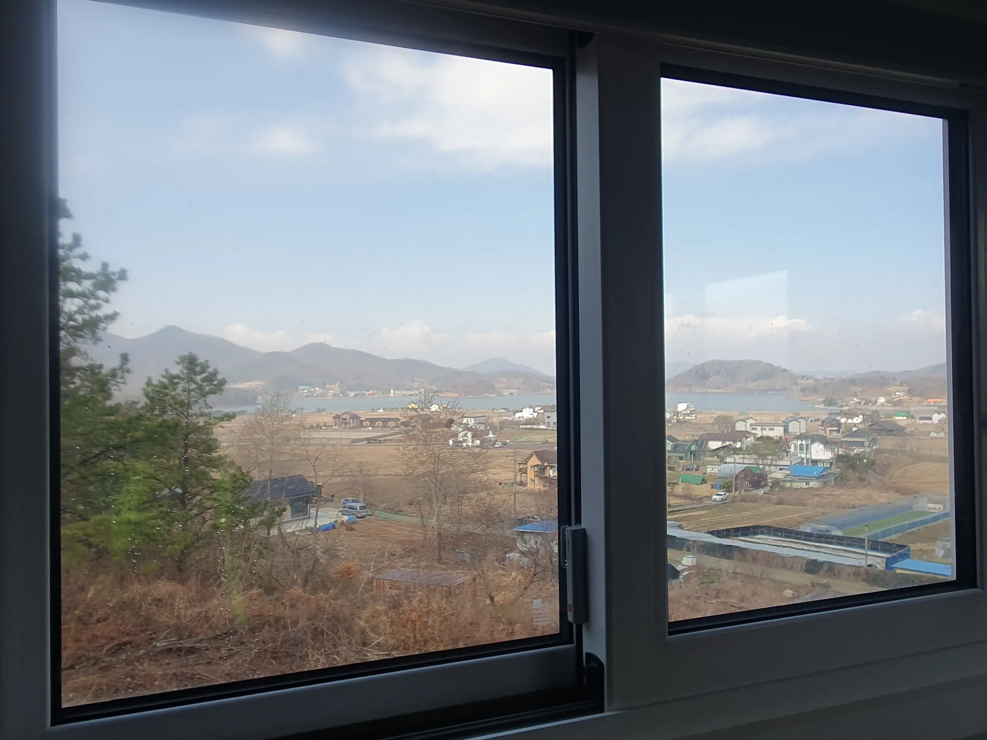 화성시 주거공간 미닫이창 너머 산과 주변 마을이 이어지는 전체 모습
