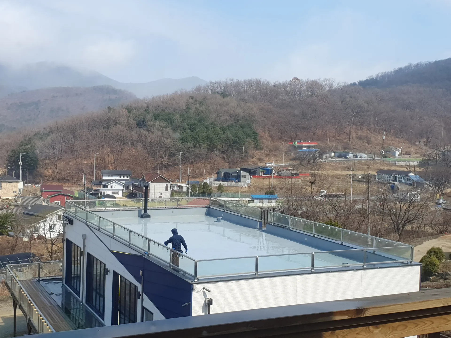 별도 방의 검은 미닫이창 너머 산과 주변 주거지가 보이는 전경